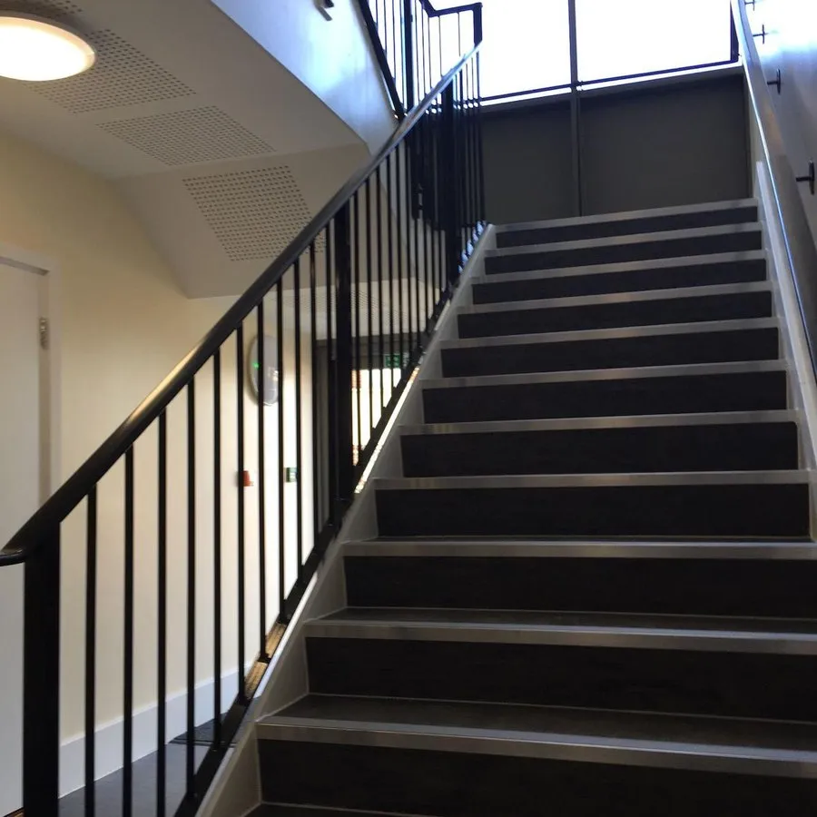 Metal staircase in Harlow with a black steel balustrade and timber treads