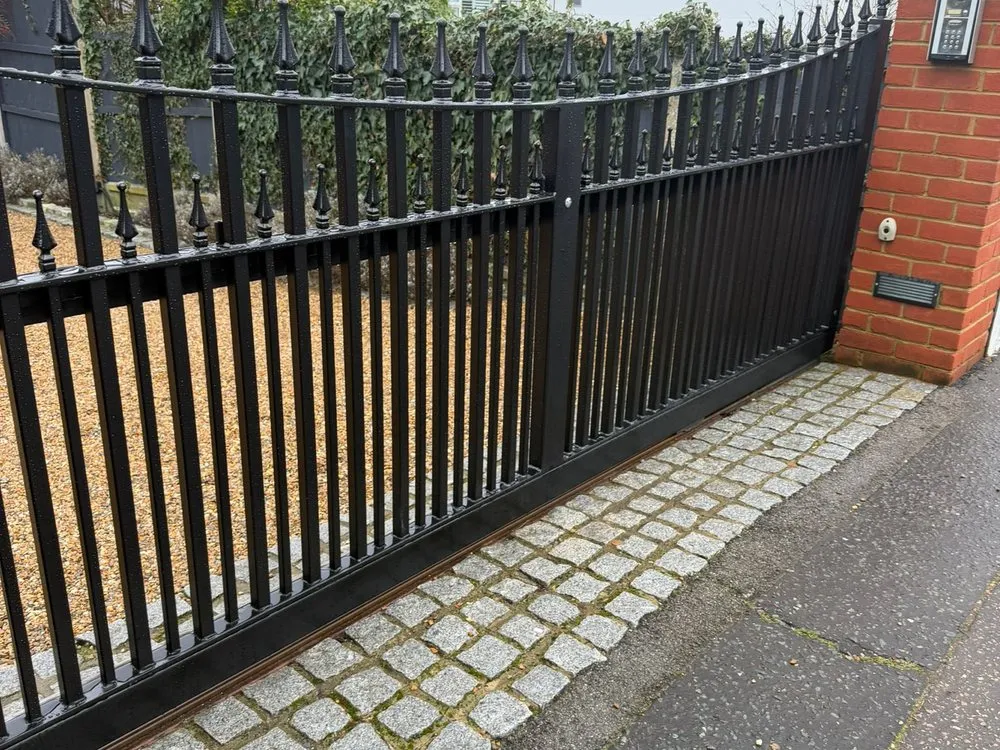 Automated driveway gates with matching railings between brick piers